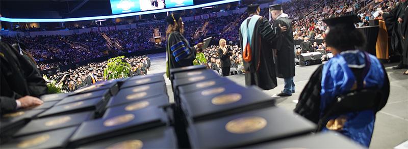 2023年毕业典礼回顾——凯布尔·达默(Cable Dahmer)的舞台上，一堆堆的文凭封面等着被分发.